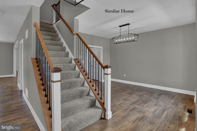 staircase featuring an inviting chandelier and dark wood-type flooring