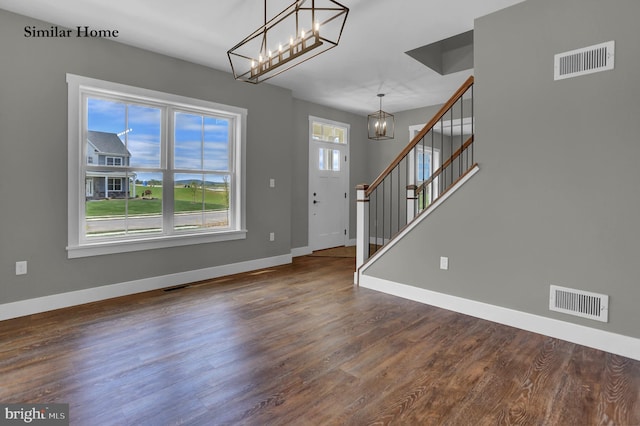 entryway with an inviting chandelier, a wealth of natural light, and dark wood-type flooring