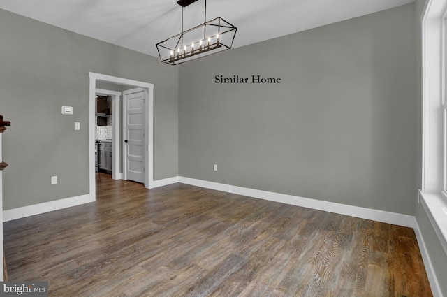 spare room with a chandelier and dark hardwood / wood-style floors