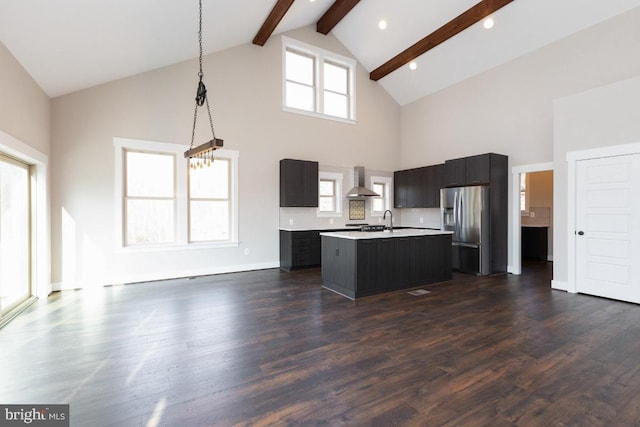 kitchen with dark hardwood / wood-style floors, a kitchen island with sink, wall chimney exhaust hood, high vaulted ceiling, and stainless steel refrigerator with ice dispenser