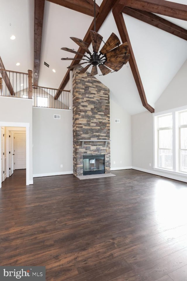 unfurnished living room featuring dark hardwood / wood-style flooring, ceiling fan, a fireplace, high vaulted ceiling, and beam ceiling