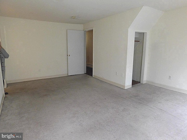 carpeted spare room with lofted ceiling