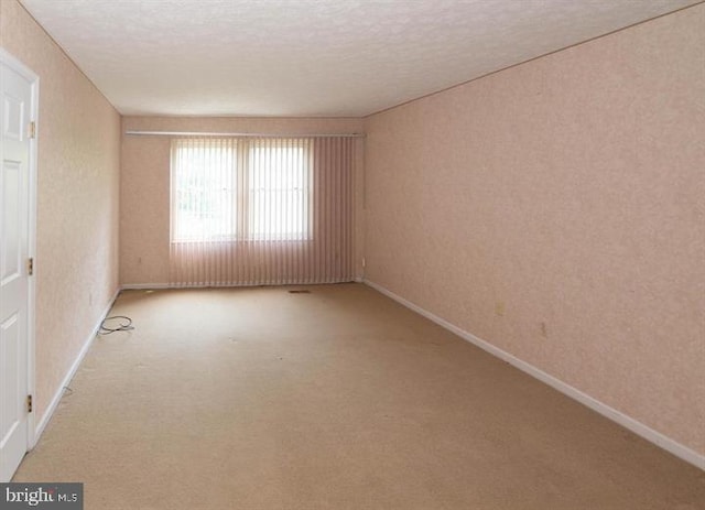 empty room featuring a textured ceiling and light colored carpet