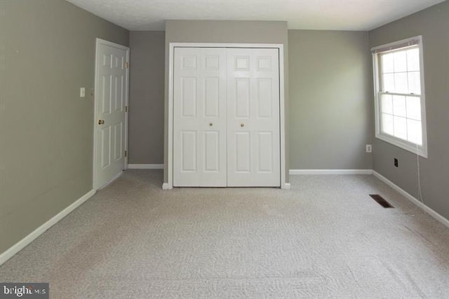 unfurnished bedroom featuring light carpet and a closet