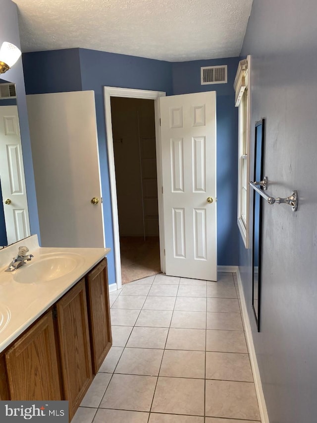 bathroom with tile patterned flooring, vanity, and a textured ceiling