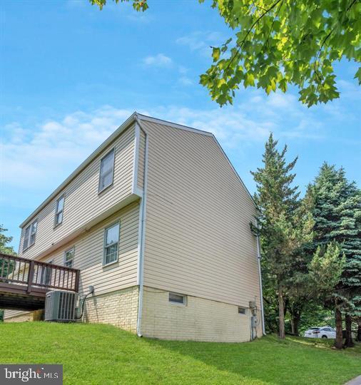 view of side of home with central AC unit, a deck, and a yard