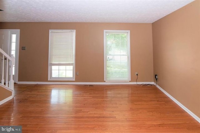 unfurnished room featuring a textured ceiling and light wood-type flooring