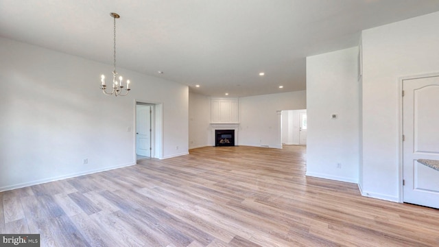 unfurnished living room featuring a chandelier and light hardwood / wood-style floors