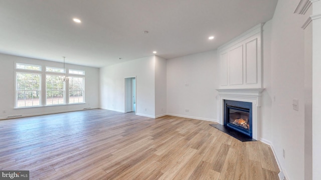 unfurnished living room featuring a notable chandelier and light wood-type flooring