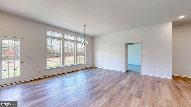 empty room with a chandelier and light wood-type flooring