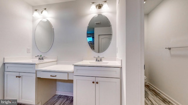 bathroom with double sink vanity, toilet, and hardwood / wood-style floors