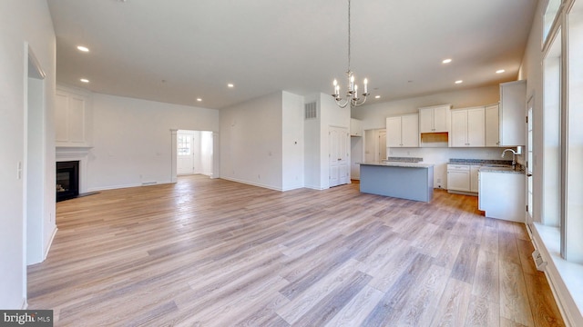 kitchen with an inviting chandelier, pendant lighting, a center island, white cabinetry, and light hardwood / wood-style flooring