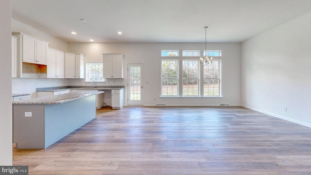 kitchen featuring an inviting chandelier, white cabinetry, and a wealth of natural light