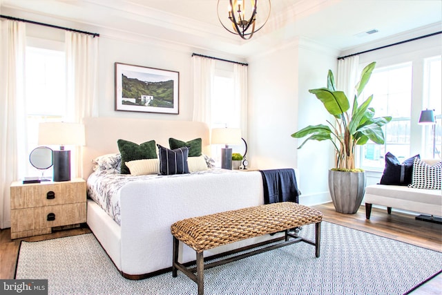 bedroom with a chandelier, light hardwood / wood-style floors, and crown molding