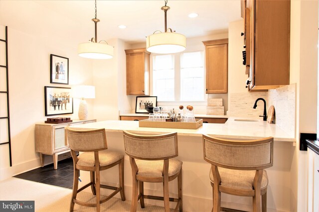 kitchen featuring sink, backsplash, a kitchen bar, and decorative light fixtures