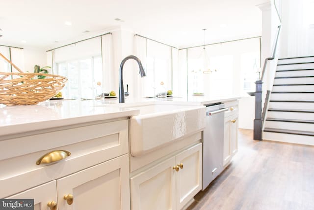 kitchen with stainless steel dishwasher, light hardwood / wood-style floors, decorative light fixtures, white cabinetry, and light stone counters