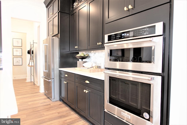 kitchen featuring backsplash, light wood-type flooring, and stainless steel appliances