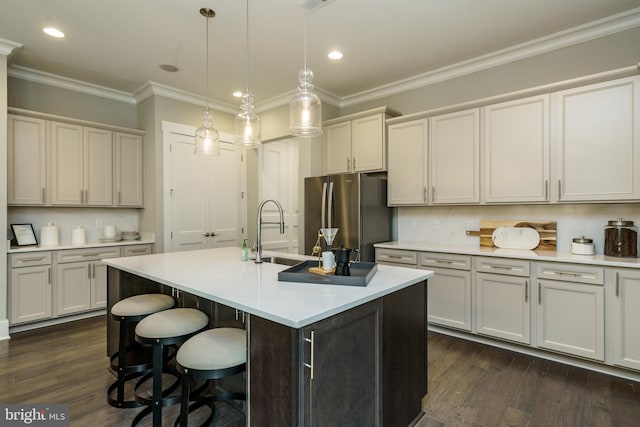 kitchen featuring sink, hanging light fixtures, dark wood-type flooring, and stainless steel refrigerator