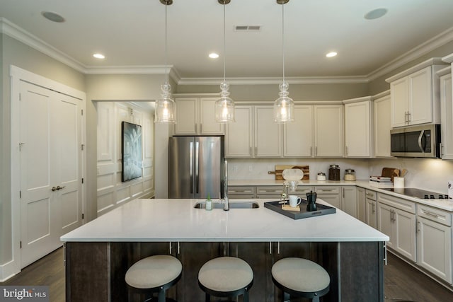 kitchen with stainless steel appliances, decorative light fixtures, dark hardwood / wood-style flooring, light stone countertops, and a center island with sink