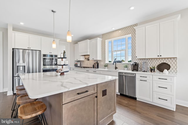 kitchen featuring a kitchen island, tasteful backsplash, stainless steel appliances, and white cabinets