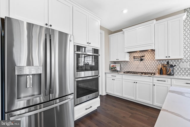 kitchen with white cabinets, appliances with stainless steel finishes, dark hardwood / wood-style floors, and tasteful backsplash