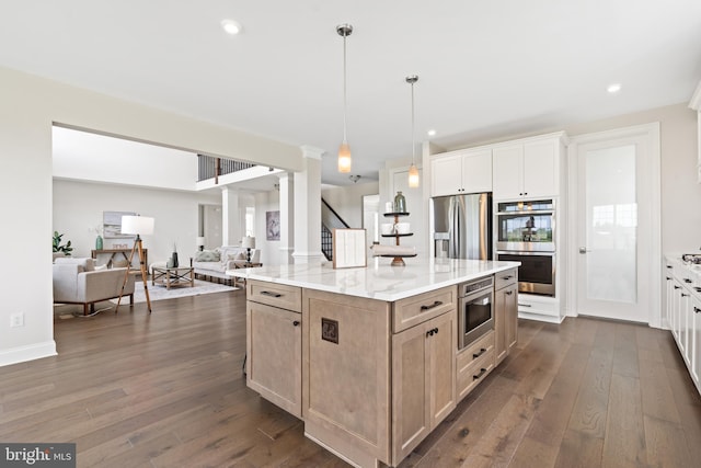 kitchen with pendant lighting, dark wood-type flooring, a kitchen island, light stone counters, and stainless steel appliances