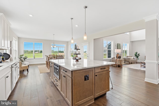 kitchen with white cabinetry, decorative light fixtures, a center island, a chandelier, and dark hardwood / wood-style flooring