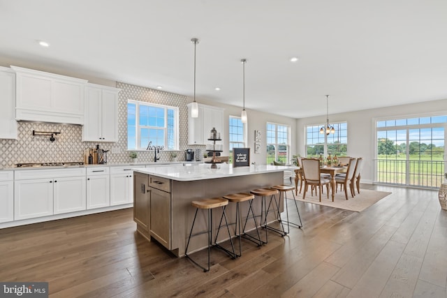 kitchen featuring white cabinetry, hanging light fixtures, dark wood-type flooring, a center island, and a breakfast bar area