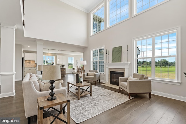 living room with a healthy amount of sunlight, dark wood-type flooring, and a towering ceiling