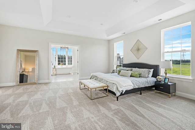 bedroom with multiple windows, a tray ceiling, a chandelier, and light colored carpet