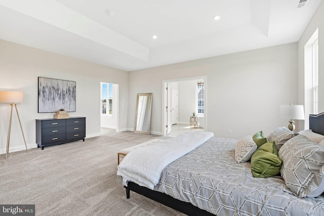 carpeted bedroom with a raised ceiling and multiple windows