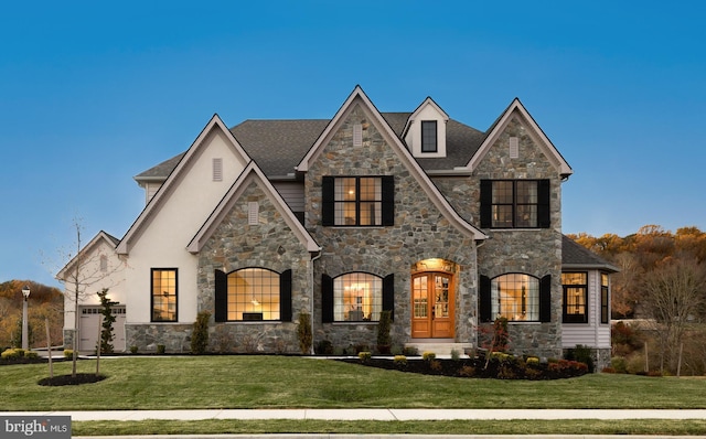 french country home featuring a garage and a front yard