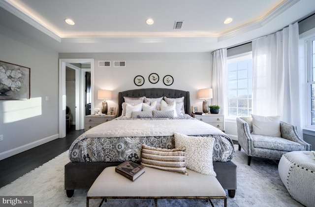 bedroom featuring hardwood / wood-style flooring, a raised ceiling, and crown molding