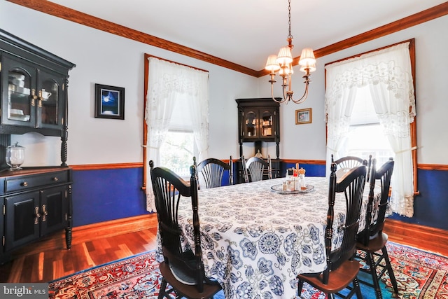 dining room with dark hardwood / wood-style floors, ornamental molding, and a notable chandelier