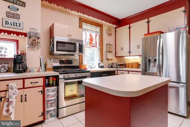 kitchen featuring light tile floors, stainless steel appliances, a kitchen island, and white cabinetry