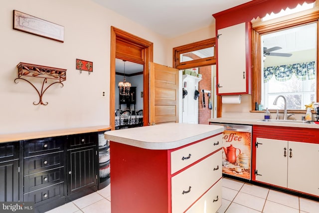 kitchen featuring white cabinets, light tile floors, dishwasher, and ceiling fan with notable chandelier