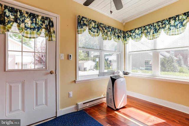 interior space with ceiling fan, a baseboard heating unit, dark wood-type flooring, and a wealth of natural light