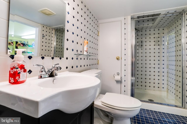 bathroom with toilet, a shower with shower door, vanity, tile walls, and tile floors