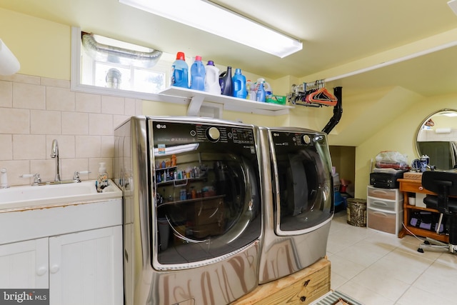 clothes washing area with light tile flooring, independent washer and dryer, and sink