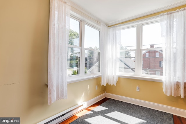 interior space featuring a baseboard radiator, dark wood-type flooring, and a healthy amount of sunlight