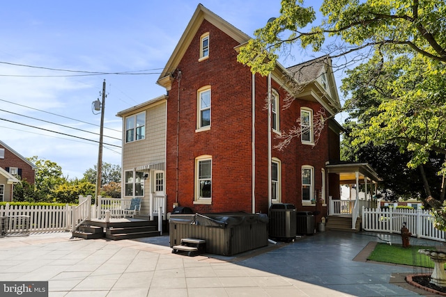 back of property with a patio, central air condition unit, a wooden deck, and a hot tub