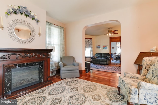 living room featuring a premium fireplace, dark hardwood / wood-style flooring, and ceiling fan