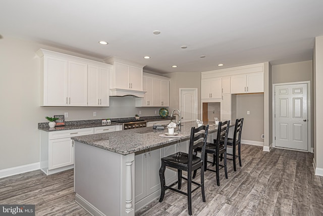 kitchen with white cabinets, a breakfast bar area, and dark hardwood / wood-style flooring