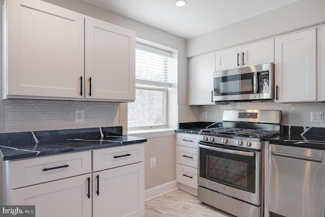 kitchen featuring white cabinets, dark stone counters, tasteful backsplash, and stainless steel appliances