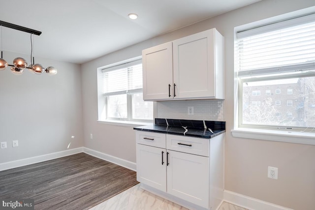 kitchen featuring decorative light fixtures, light hardwood / wood-style floors, white cabinets, a chandelier, and tasteful backsplash