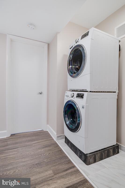 laundry area featuring stacked washer and dryer and hardwood / wood-style floors