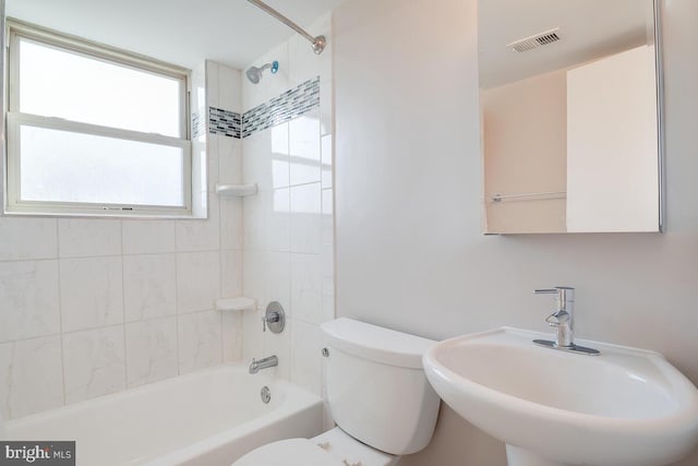 full bathroom featuring tiled shower / bath combo, toilet, and sink