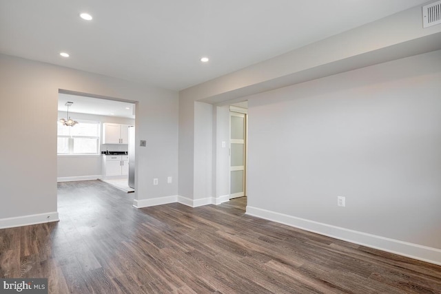 empty room featuring dark hardwood / wood-style floors and a chandelier