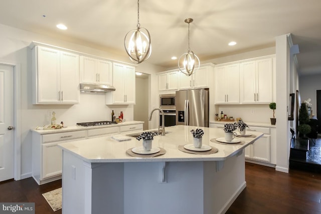 kitchen featuring pendant lighting, an island with sink, stainless steel appliances, and white cabinetry