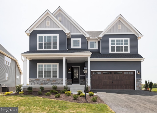 craftsman house with a garage, a porch, a front lawn, and cooling unit